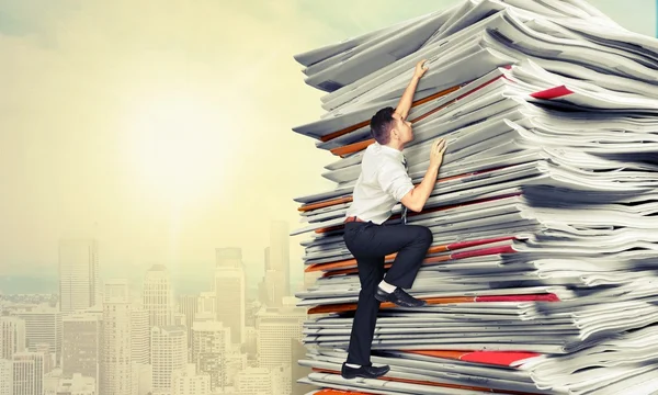 Businessmen climbing up a pile of documents — Stock Photo, Image