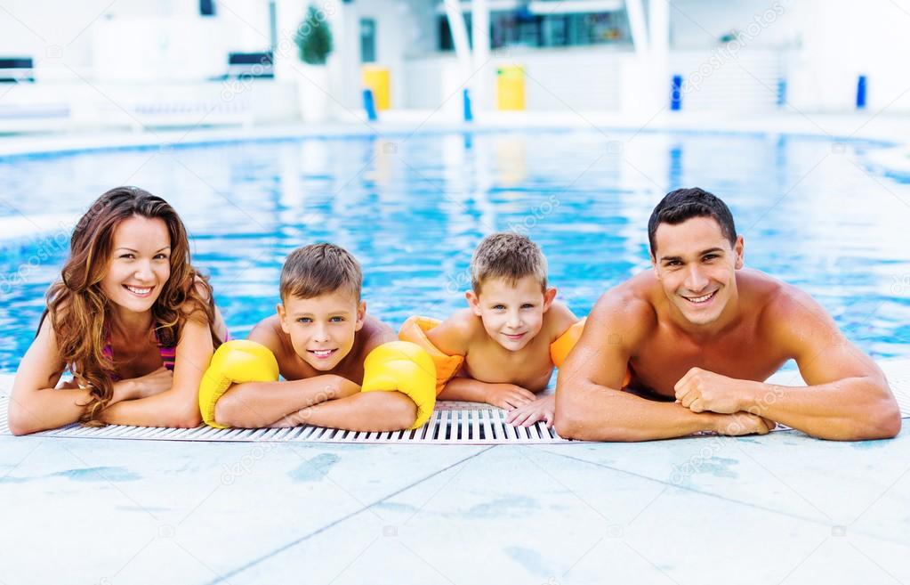 Happy family playing in swimming pool. 