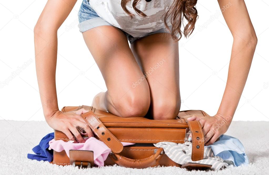 young  woman packing suitcase 