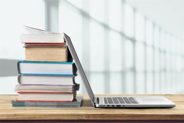 Dizüstü bilgisayar ile kitap yığını