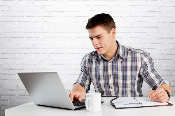 Jovem feliz trabalha em seu laptop — Fotografia de Stock