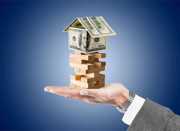 Businessman and tower of wooden blocks wih dollars — Stock Photo, Image