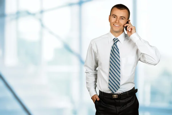 Handsome young businessman talking on phone at office — Stock Photo, Image