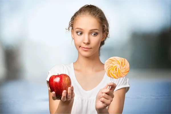 Kobieta trzyma jabłko i cukierki w ręce — Zdjęcie stockowe