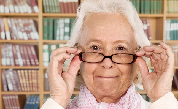 Mulher de cabelo cinza em óculos na biblioteca — Fotografia de Stock