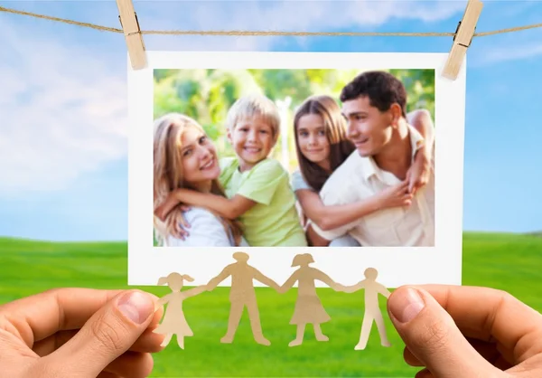 Hands holding photo of  cheerful family — Stock Photo, Image