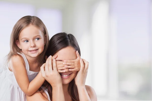 Young daughter closes hands eyes mom