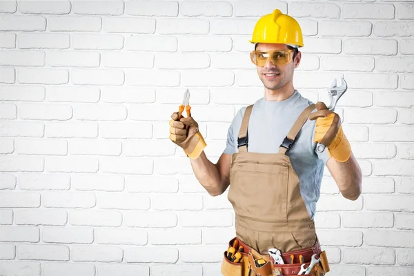 Construtor em pé uniforme e segurando ferramentas — Fotografia de Stock