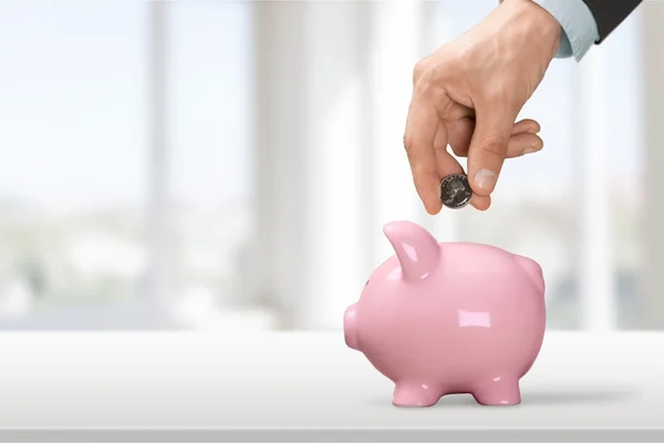 Mão colocando moeda para o banco porquinho — Fotografia de Stock