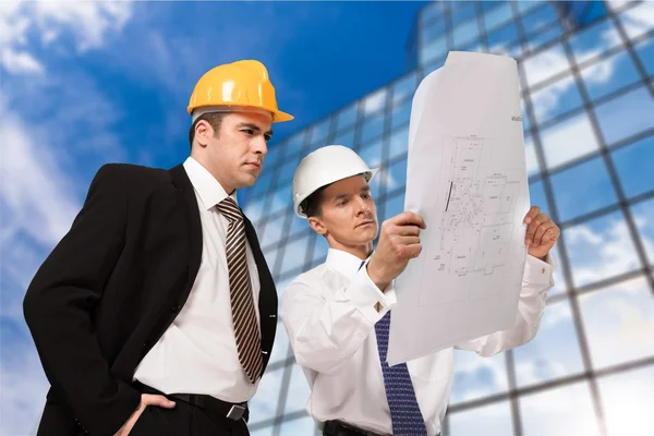 Ingenieure mit Blaupause tragen Helme — Stockfoto