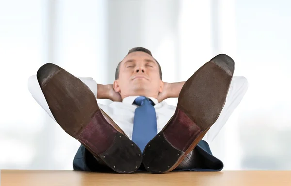 Бизнесмен отдыхает на стуле с ногами на столе — стоковое фото