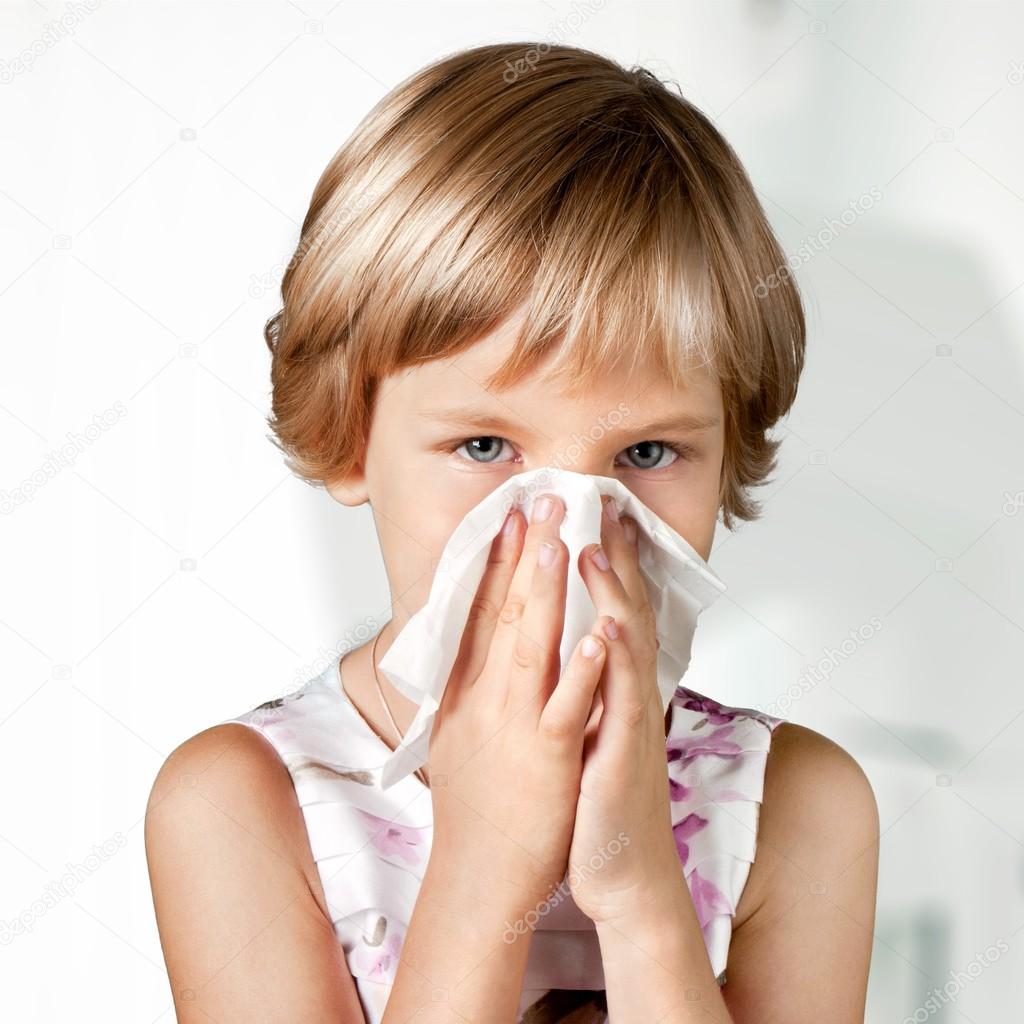 Young girl blowing her nose.