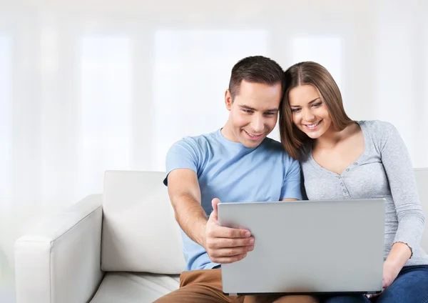 Casal sorrindo com laptop no sofá — Fotografia de Stock