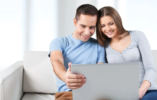 Casal sorrindo com laptop no sofá — Fotografia de Stock