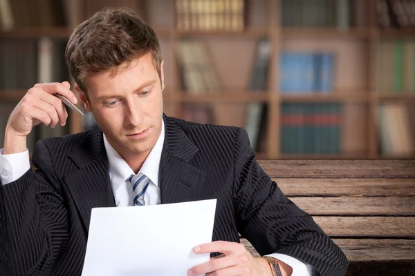 Schöner junger Geschäftsmann liest Bericht — Stockfoto