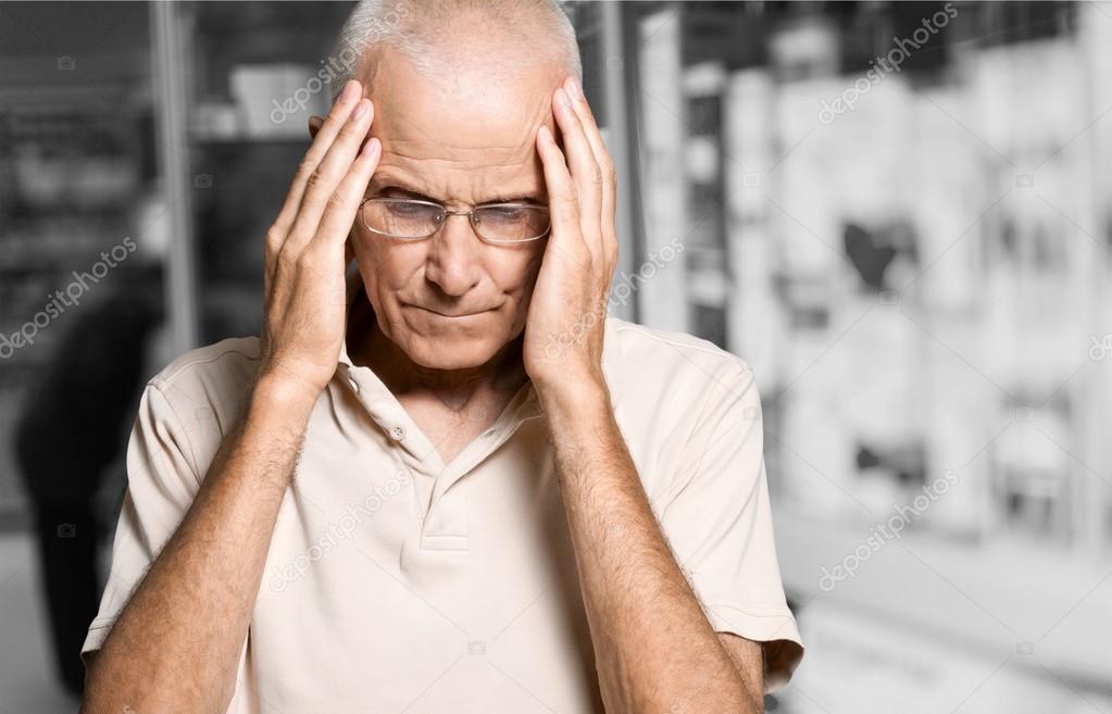 mature man holding his head in pain