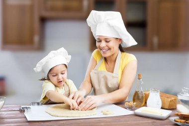 Smiling women and a child have fun baking together with dough at home kitchen.