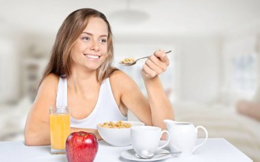 A young attractive happy woman who eats healthy food in house room