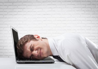 Genç işadamının kafası dizüstü bilgisayarla kaya arasına sıkışmış.