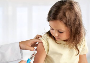 Doktor, beyaz arka planda izole edilmiş küçük bir kızı aşılıyor.