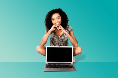 Yerde dizüstü bilgisayarı açık bir kadın çalışıyor.