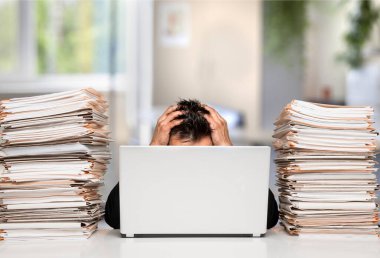 Yorgun, genç bir iş adamı ve yığınla evrak.