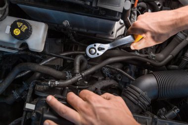 Otomobil tamircisi bir araç ile bir araba motoru üzerinde çalışıyor