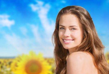 Mavi arka planda ayçiçeği olan genç ve güzel bir kadın.