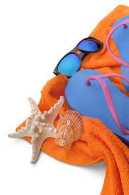 Parmak arası terlik, havlu, deniz kabuğu ve güneş gözlüğü.