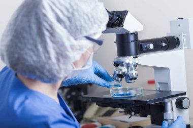 Bilim adamı bir mikroskobun arkasında çalışıyor.