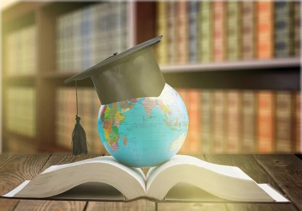 Education to learn study in world. Graduated student studying abroad international idea. Master degree hat on top globe book. Concept of graduate educational for long distane learning anywhere anytime