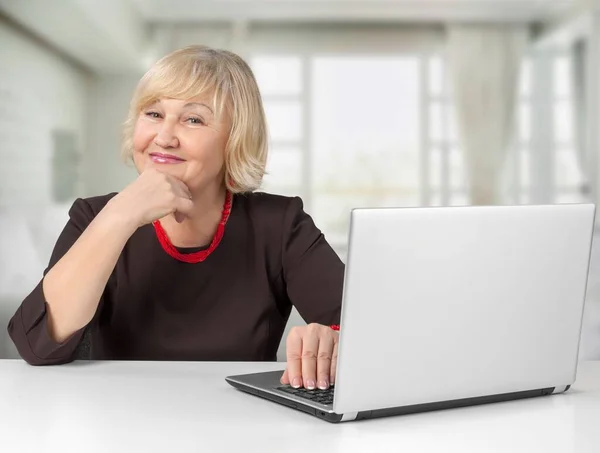 Lächelnd Sitzt Eine Reife Frau Einem Schreibtisch Mit Laptop — Stockfoto