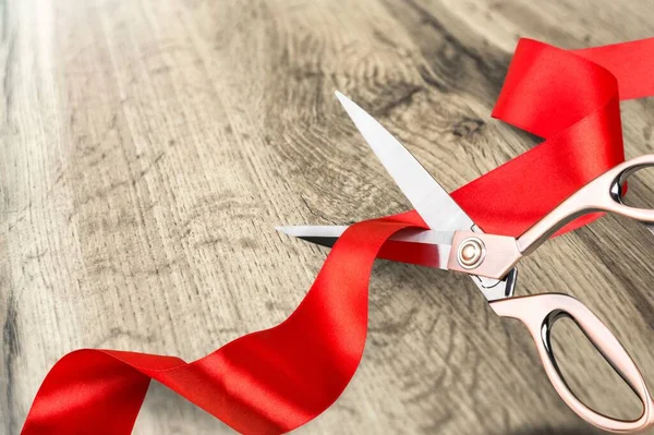 Masanın üzerindeki kırmızı kurdeleyi kesen makas.