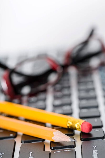 Крупный план клавиатуры с очками и карандашами