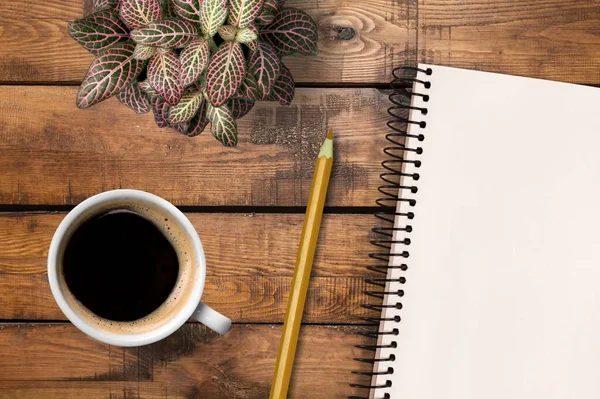 Bir defter, bir fincan kahve ve bir kalemle çalışma yeri.