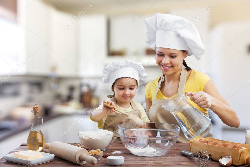 Little girl holding whisk stirring eggs in bowl making with mommy mixture for morning pancakes, mother daughter preparing sweet pie using flour sugar milk sitting on chairs at table in modern kitchen