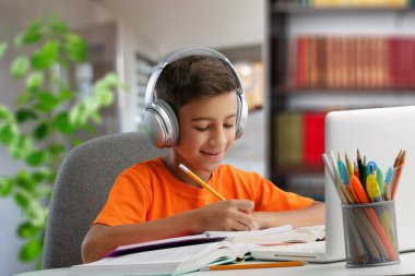 Genç, mutlu, mutlu, kulaklık takan bir öğrenci internette sohbet toplantısında konuşuyor.