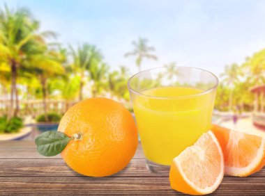 Bir bardak taze portakal suyu ve masasında portakal dilimleri..