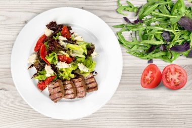 Mutfak masasındaki beyaz tabakta yeşil salata. Sağlıklı yiyecekler, temiz yeme konsepti.