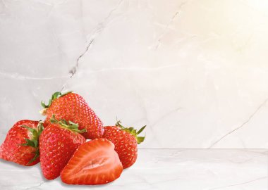 Masanın üzerinde taze kırmızı çilekler ve yeşil yapraklar var.