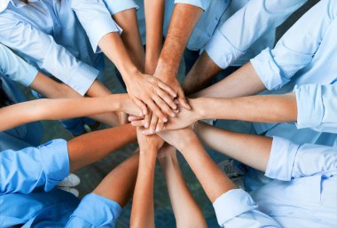 Genç iş adamları ellerini birleştiriyor. Arka planda el yığını.