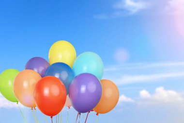 Mavi gökyüzünde helyumlu ve bulutlu bir grup renkli balon.