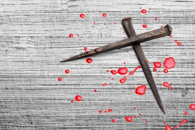 Paslı çivilerle yapılmış Hristiyan haçı, masanın üzerine kan damlaları.