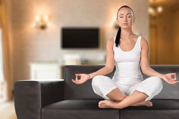 Geconcentreerde Jonge Vrouw Zitten Bank Met Gekruiste Benen Oefenen Yoga — Stockfoto