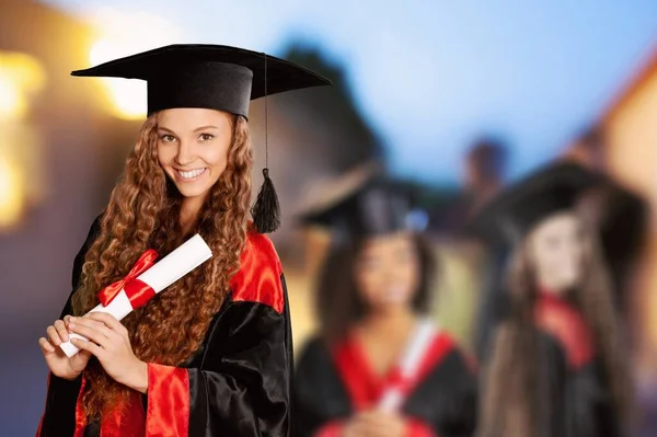 Portrait of a confident and proud female student in a university graduate gown and with a diploma