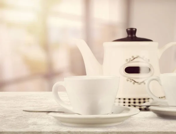 Herbal tea with white tea cups and teapot on a kitchen desk