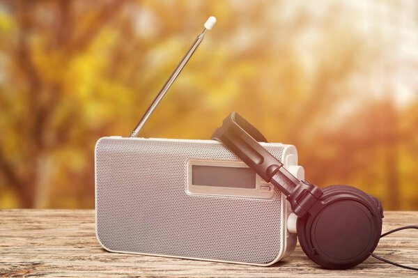 Большие наушники рядом со старомодным радио на открытом фоне.