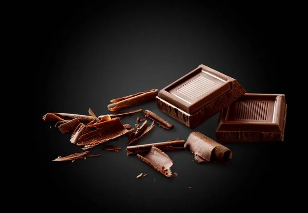 チョコレートピースと暗い背景にカールとココアパウダー — ストック写真
