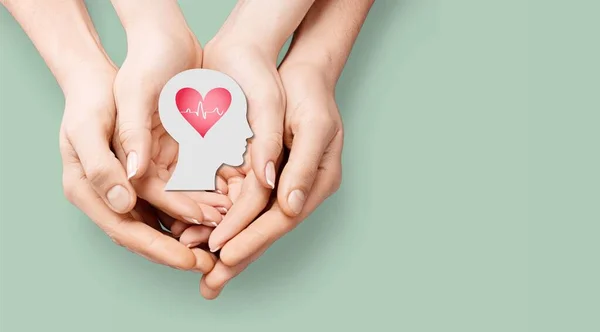 Adult and children hands holding paper head and heart,