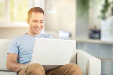 Neşeli iş adamı, parlak ofis alanında dizüstü bilgisayar kullanıyor..